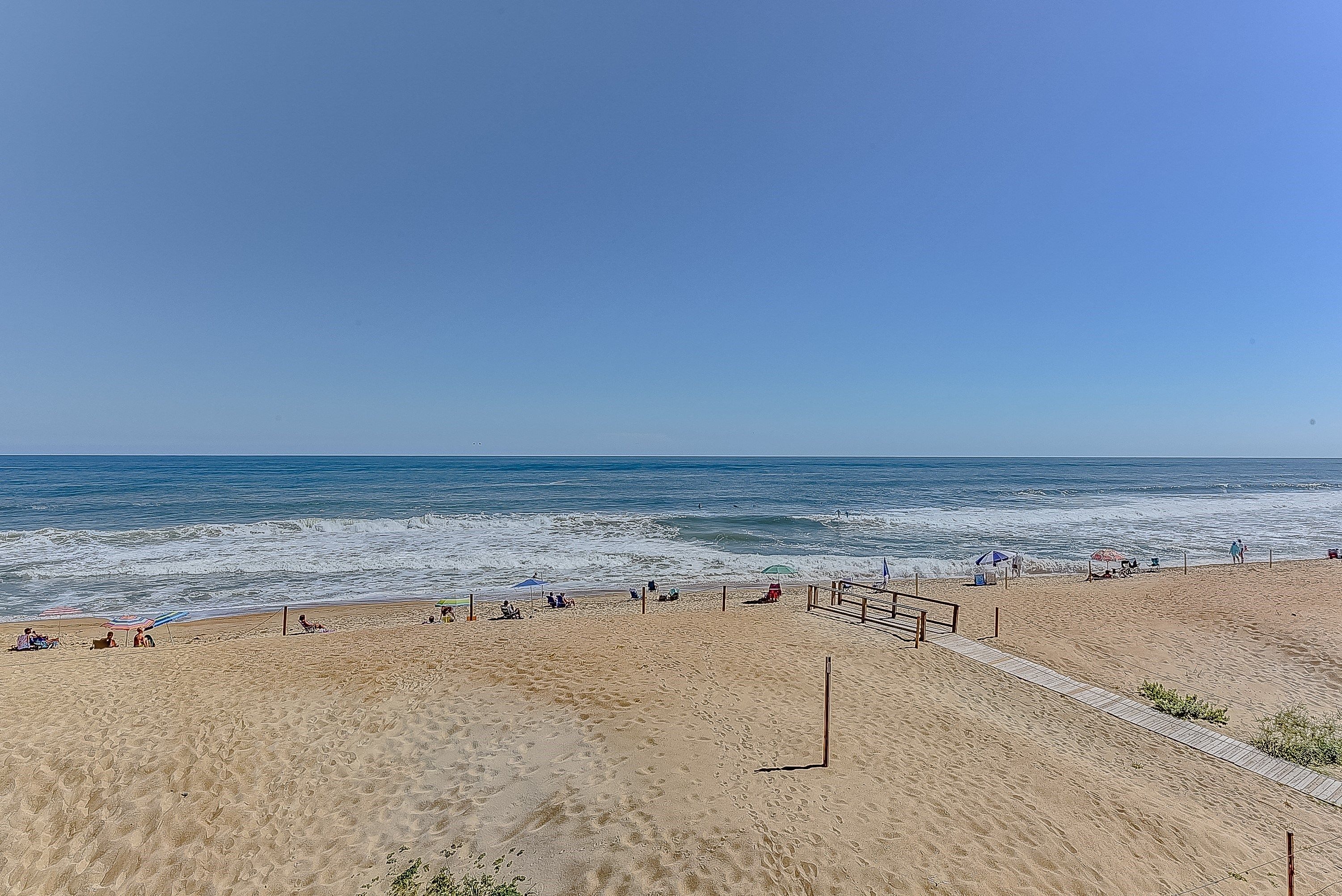 Een strand met een houten looppad en parasols.