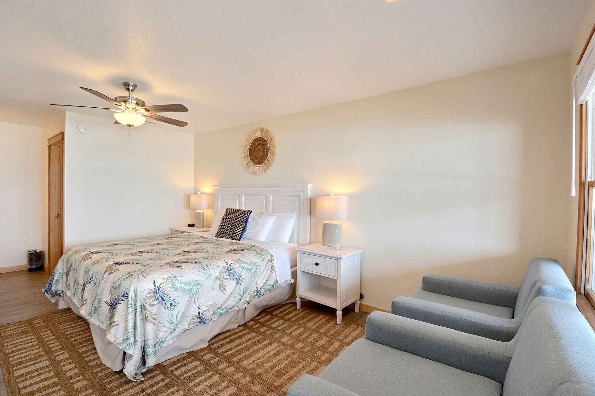 A bedroom with a bed, a nightstand, a lamp, a ceiling fan, and a window.