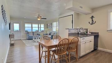 A spacious living area with a dining table and chairs, a kitchen with a sink and cabinets, and a ceiling fan.
