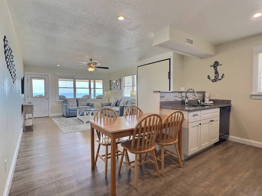 A spacious living area with a dining table and chairs, a kitchen with a sink and cabinets, and a ceiling fan.