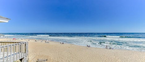 A beach with a wooden walkway and a view of the ocean.