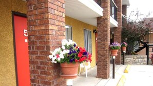 A building with a brick facade, a red door, and flower planters on the sidewalk. - Color Country Motel (Panguitch)