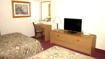 Une chambre d’hôtel avec deux lits, un bureau avec une chaise, une télévision et une commode.