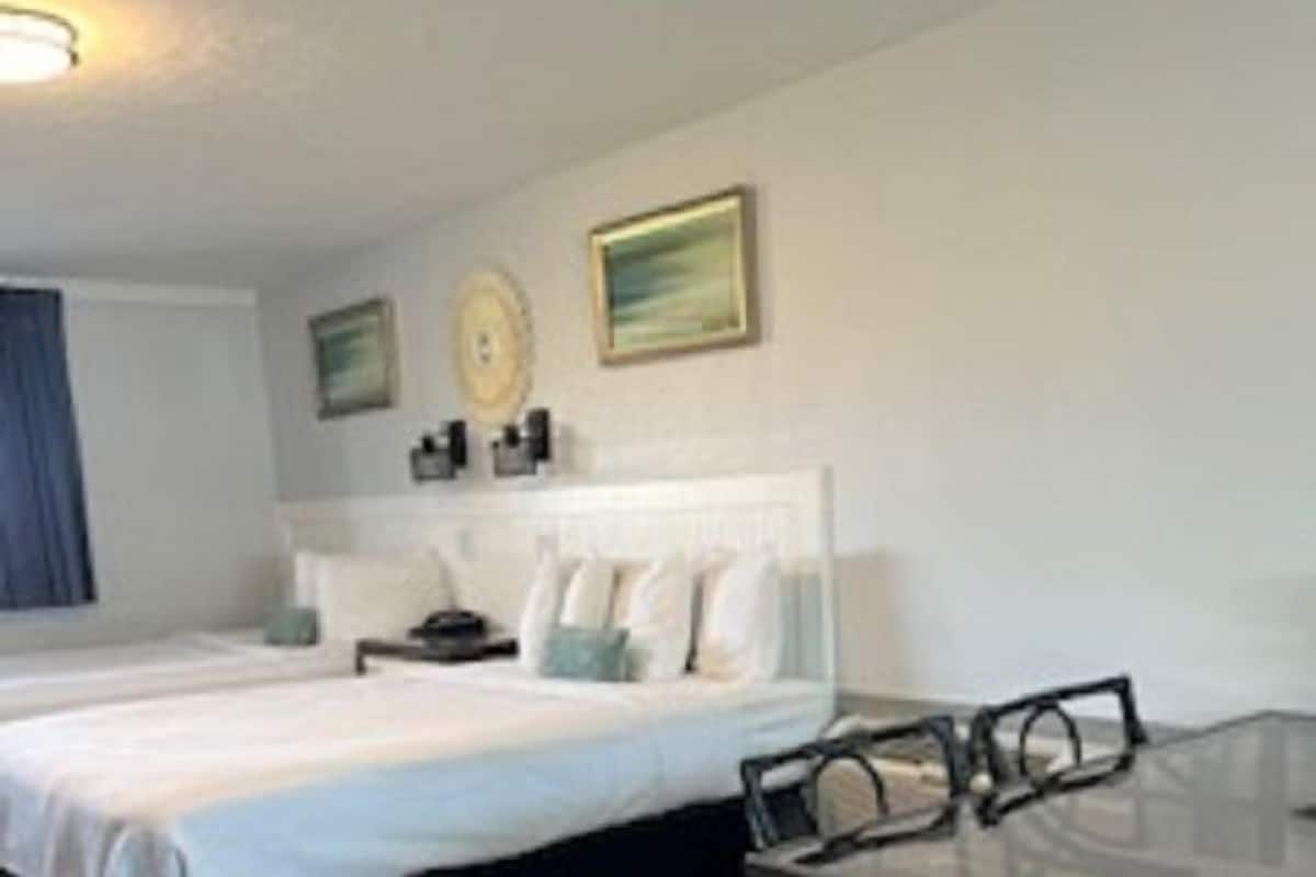 A hotel room with two beds, a dining table, and a small kitchenette.