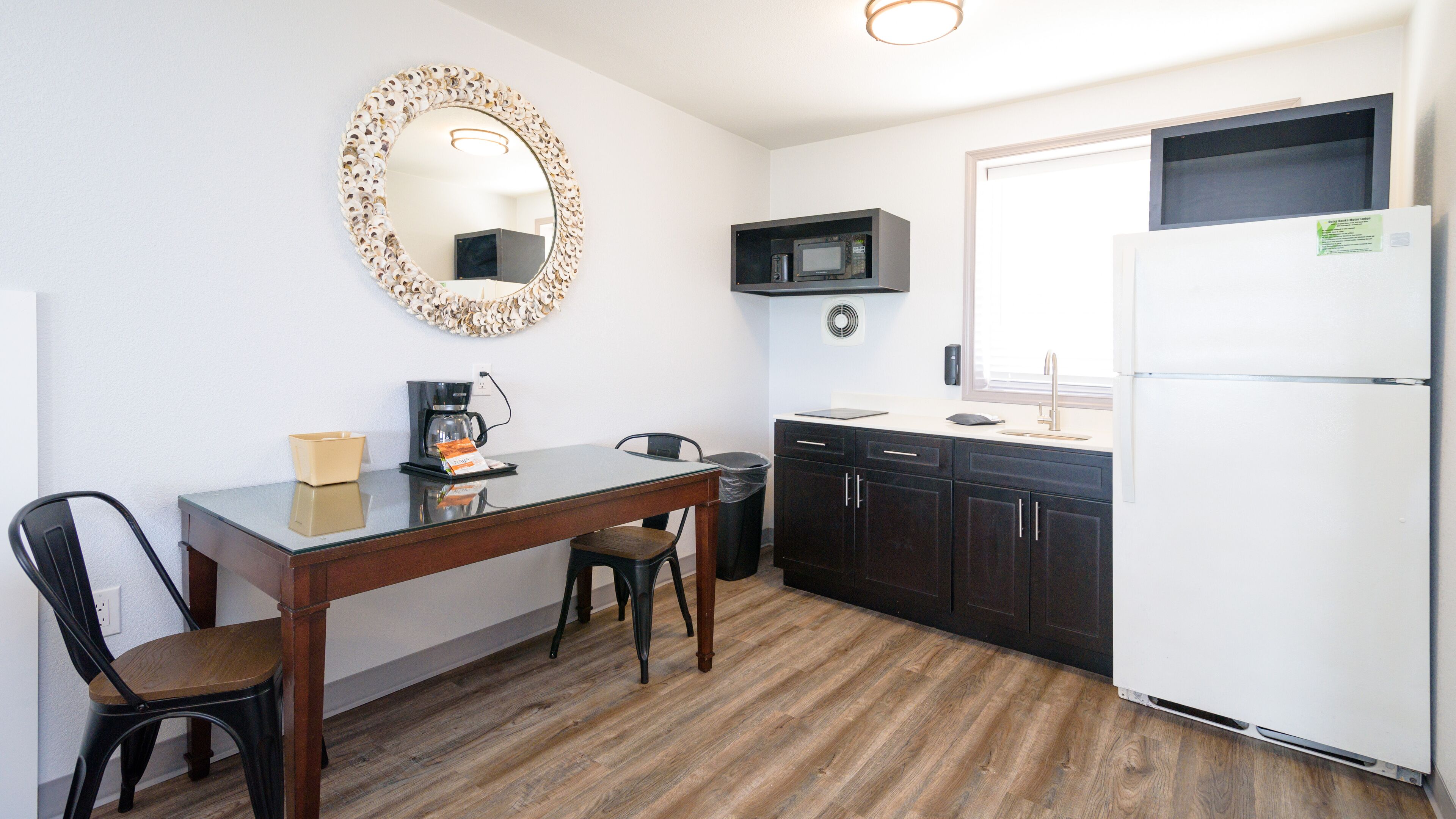 A compact kitchen with a dining table, chairs, a coffee maker, a microwave, and a refrigerator.