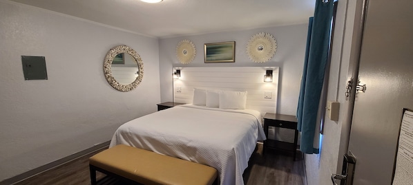 Habitación de hotel con una cama grande, un banco, un espejo y decoración en la pared.