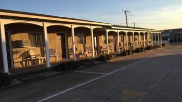 A motel with multiple rooms, each with a porch and chairs.