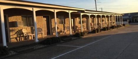 A motel with multiple rooms, each with a porch and chairs.