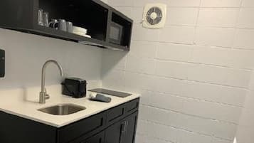Una cocina compacta con un lavamanos doble, armarios oscuros y un microondas sobre la encimera.