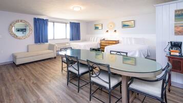A hotel room with a dining area, a bed, a sofa, and a coffee machine.