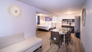 A compact hotel room with a bed, a dining table with chairs, a kitchenette, and a sofa. - Outer Banks Motor Lodge (Kill Devil Hills)