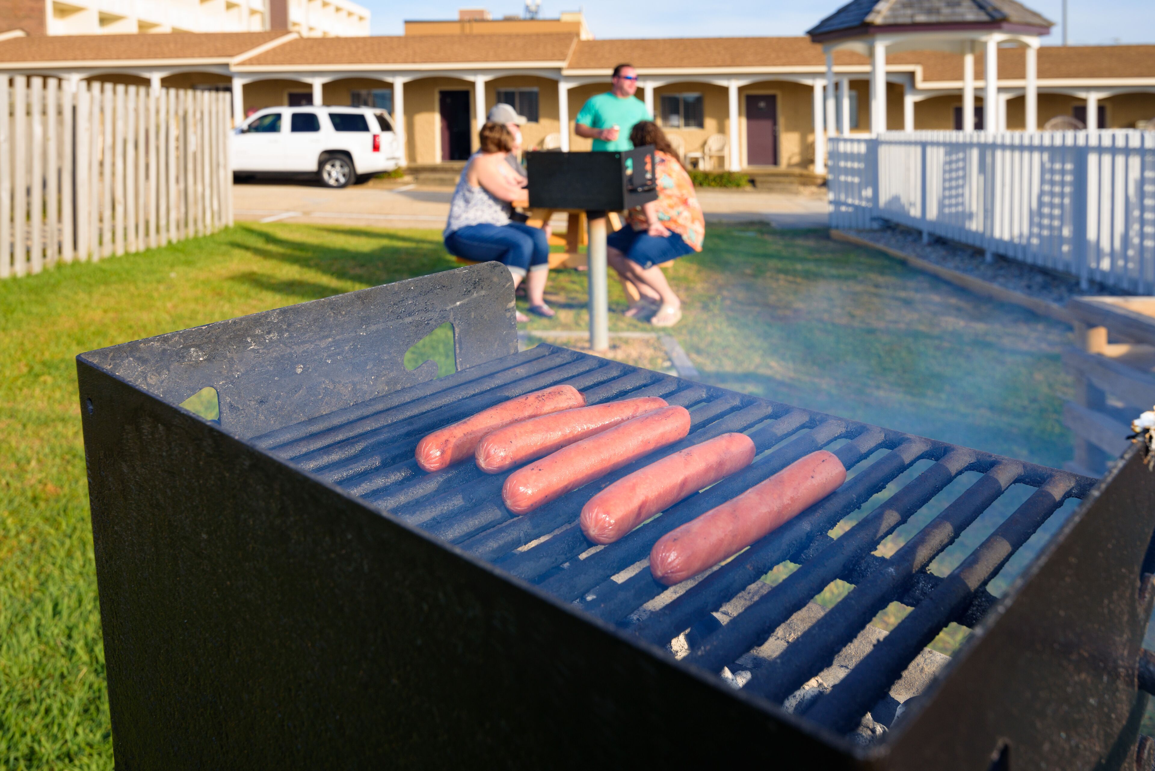 A barbecue grill with hot dogs being cooked.