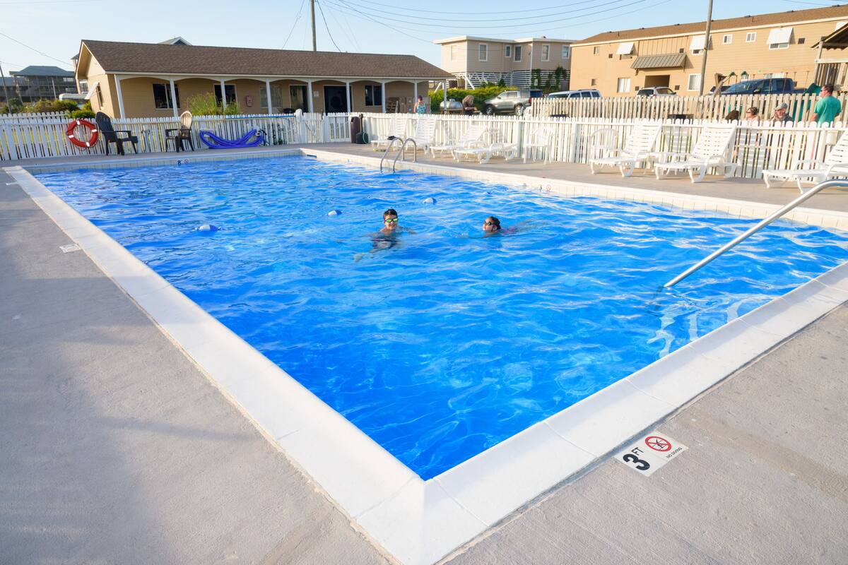 A rectangular swimming pool with a white deck and a no diving sign.