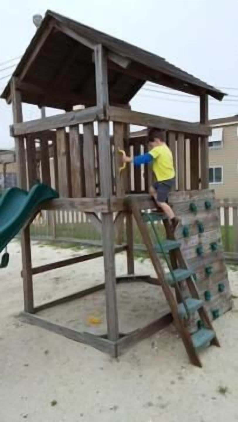 A wooden play structure with a slide and climbing elements.
