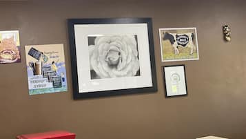 A wall with various framed items, including a rose, a Hershey's advertisement, and a certificate.