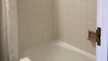 A bathroom with a bathtub, a toilet, and a shower curtain.