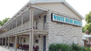 Un edificio a due piani con un balcone e un cartello con scritto 'WHITE ROSE MOTEL'.