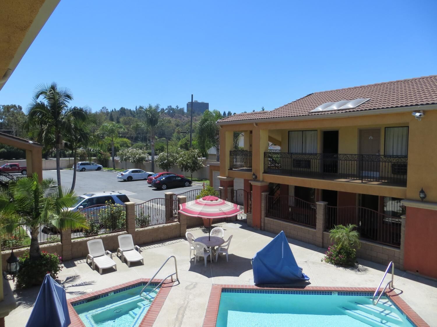 A hotel with a pool area, lounge chairs, and a view of the parking lot and surrounding buildings.