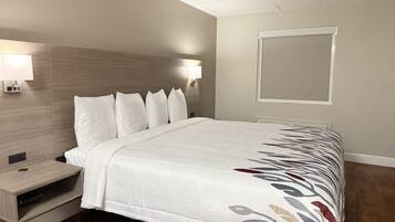 A neatly made bed with a patterned bedspread, a bedside table with a lamp, and a wall-mounted light fixture.