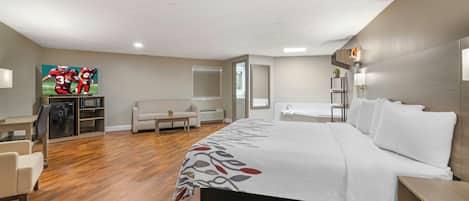 Habitación de hotel con cama, escritorio, silla, sofá, televisor y baño.