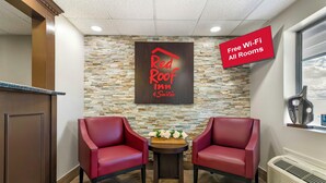 A Red Roof Suites hotel lobby with two leather chairs, a stone wall, and a sign indicating free Wi-Fi in all rooms. - Red Roof Inn & Suites Swansea (Swansea)