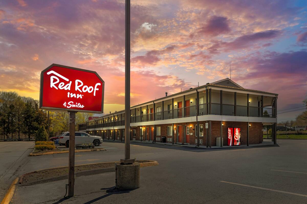 A Red Roof Inn with a two-story building, a parking lot, and a clear sky.
