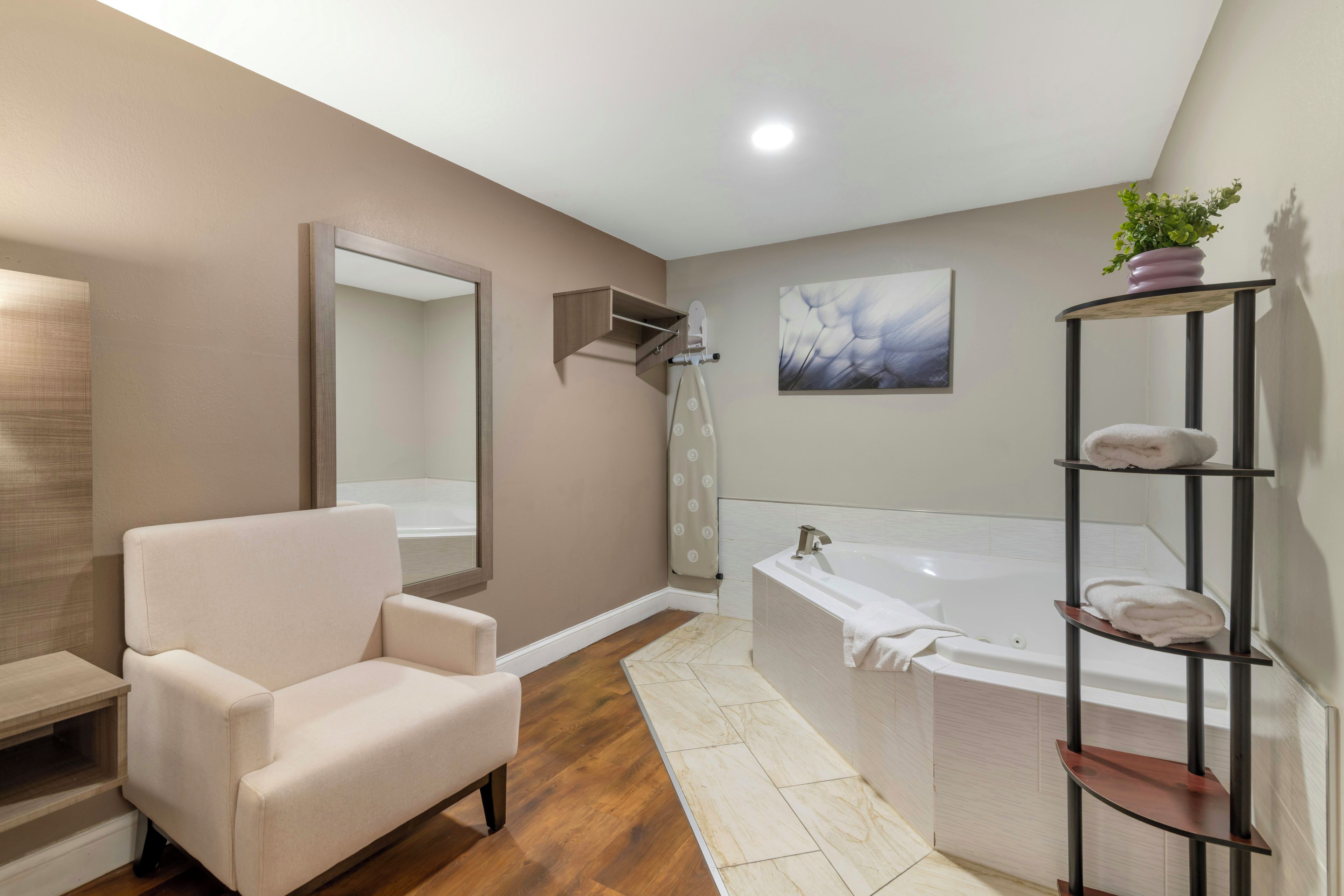 Un baño moderno con una bañera, un tocador con espejo, una silla y un estante con toallas.