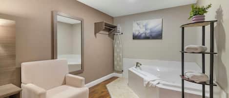 Un baño moderno con una bañera, un tocador con espejo, una silla y un estante con toallas.