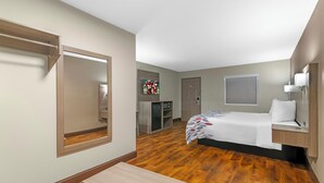 A hotel room with a bed, bedside table, desk, mirror, wardrobe, and a television. - Red Roof Inn & Suites Swansea (Swansea)