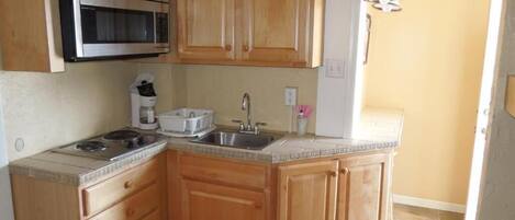 A kitchen with wooden cabinets, a stainless steel microwave, a sink, and a stove.