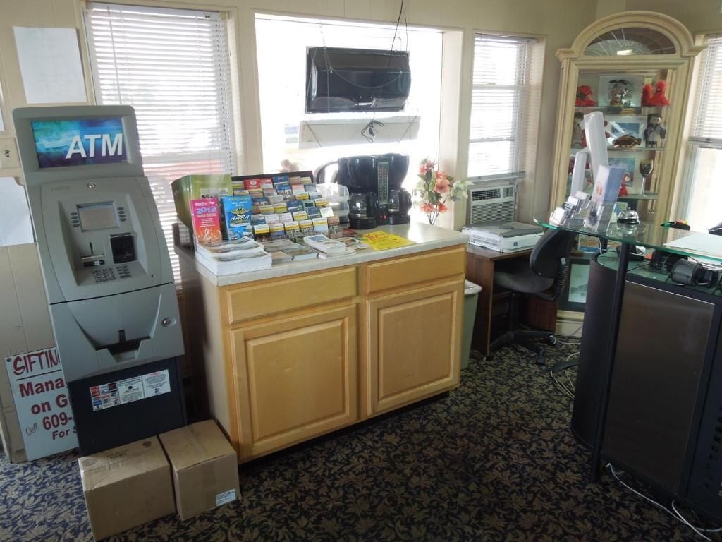 A small room with a kitchenette, an ATM, and a window with blinds.