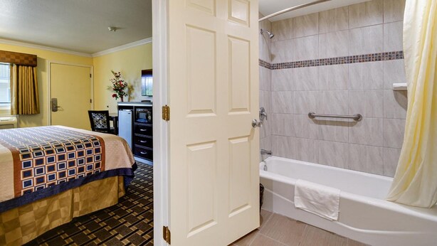 A hotel room with a bed, a bathroom with a bathtub and shower, and a desk with a chair.