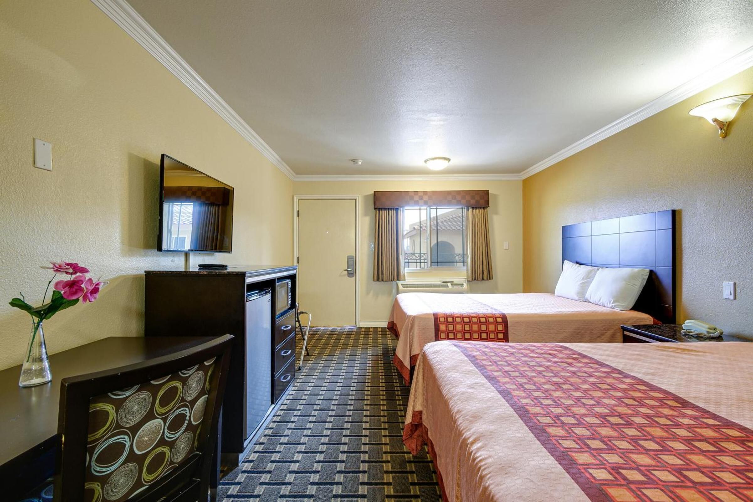 Habitación de hotel con dos camas, un escritorio, un aparador y un espejo.