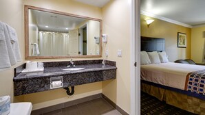 A hotel bathroom with a granite countertop sink, a mirror, a towel rack, and a shower curtain.