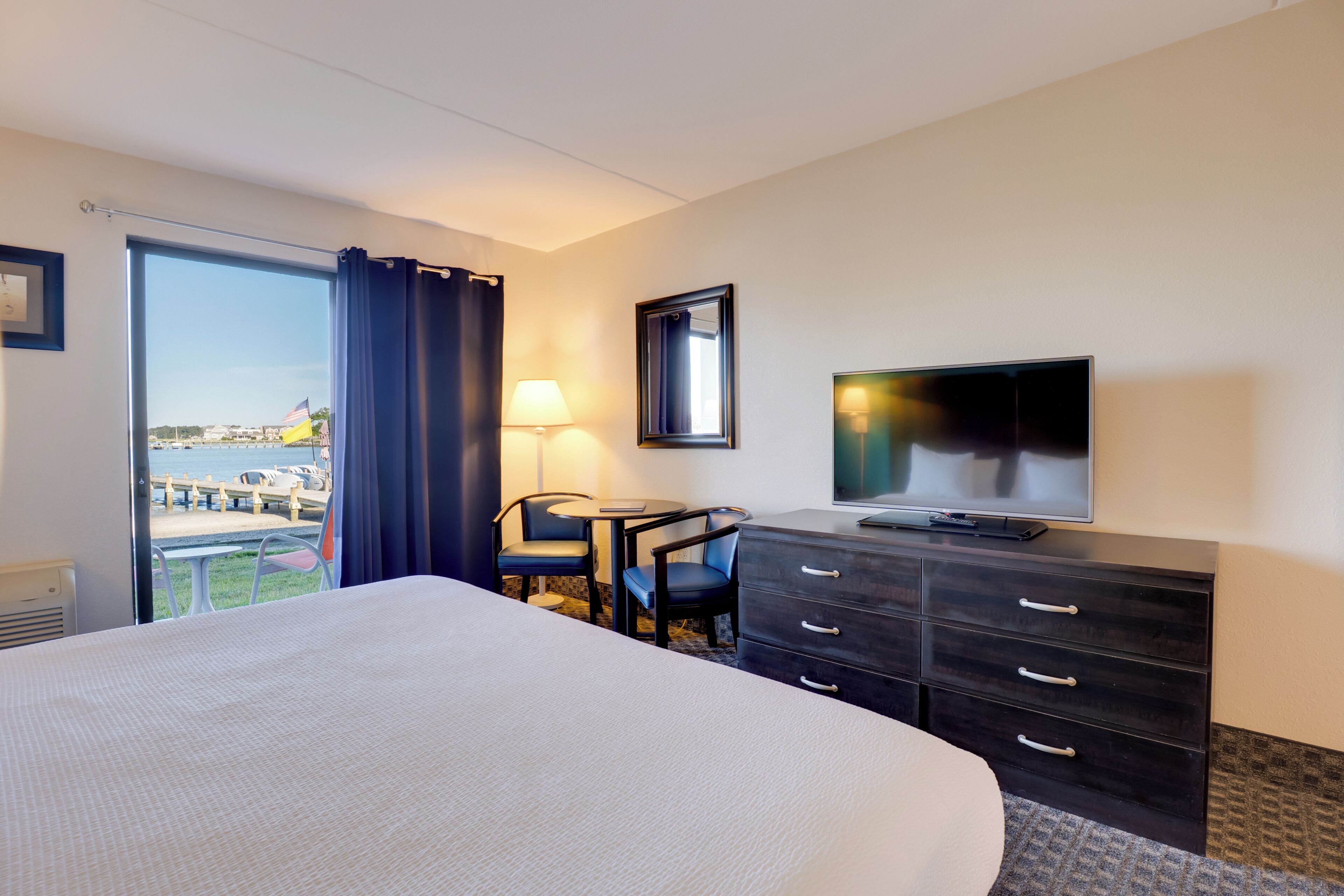Habitación de hotel con una cama grande, un escritorio con dos sillas, una televisión y vistas al exterior.