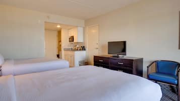 Une chambre d’hôtel avec deux lits, une télévision, un bureau avec une chaise et une kitchenette.