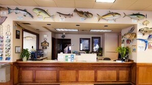 A reception area with a wooden counter, fish wall art, and a plant. - Benny's Colville Inn (Colville)