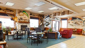 A restaurant with a stone fireplace, fish wall art, and red seating. - Benny's Colville Inn (Colville)
