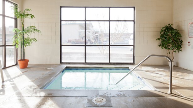 An indoor swimming pool with a view of the outside through large windows, a metal pool ladder, and potted plants. - Benny's Colville Inn (Colville)