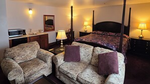 A hotel room with a four-poster bed, two floral-patterned sofas, a coffee machine, a lamp, and a small table. - Benny's Colville Inn (Colville)