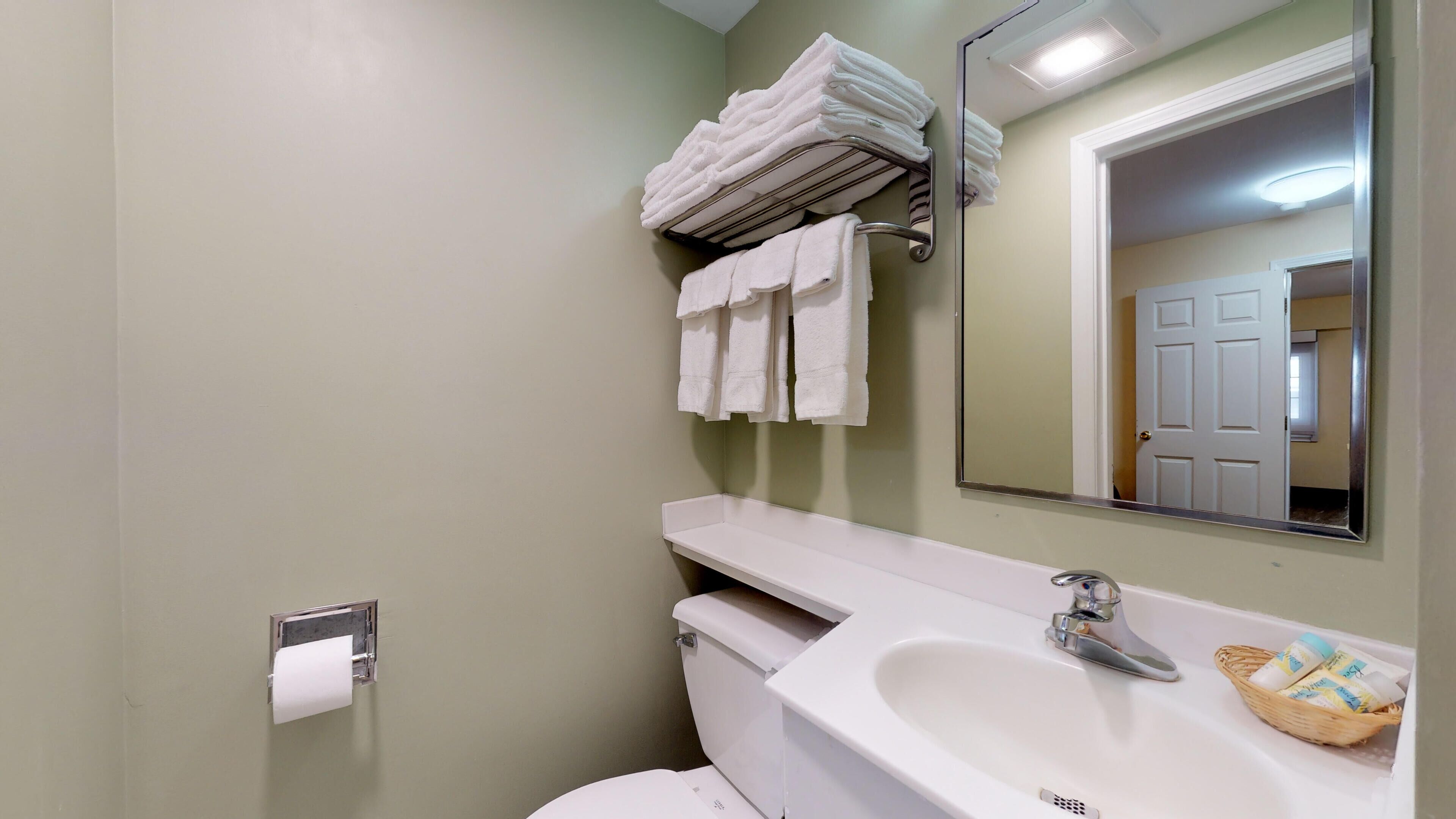 Ein Badezimmer mit Toilette, Waschbecken, Handtuchhalter und Spiegel.