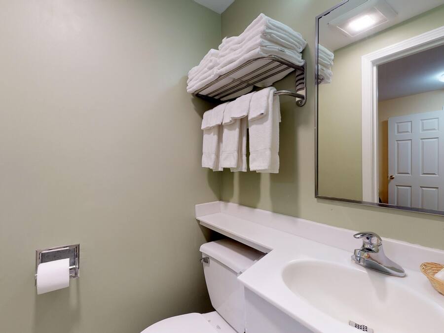 Ein Badezimmer mit Toilette, Waschbecken, Handtuchhalter und Spiegel.
