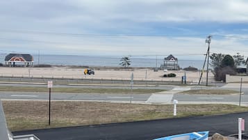 Blick auf einen Strand mit Parkplatz, einem Boot und einem Gebäude mit rotem Dach.