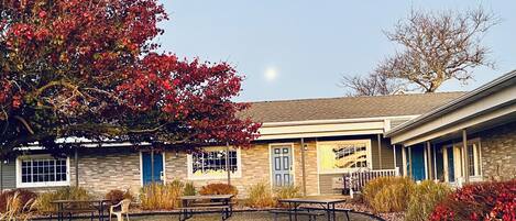 A building with a brick facade, multiple windows, and a covered patio area with picnic tables.