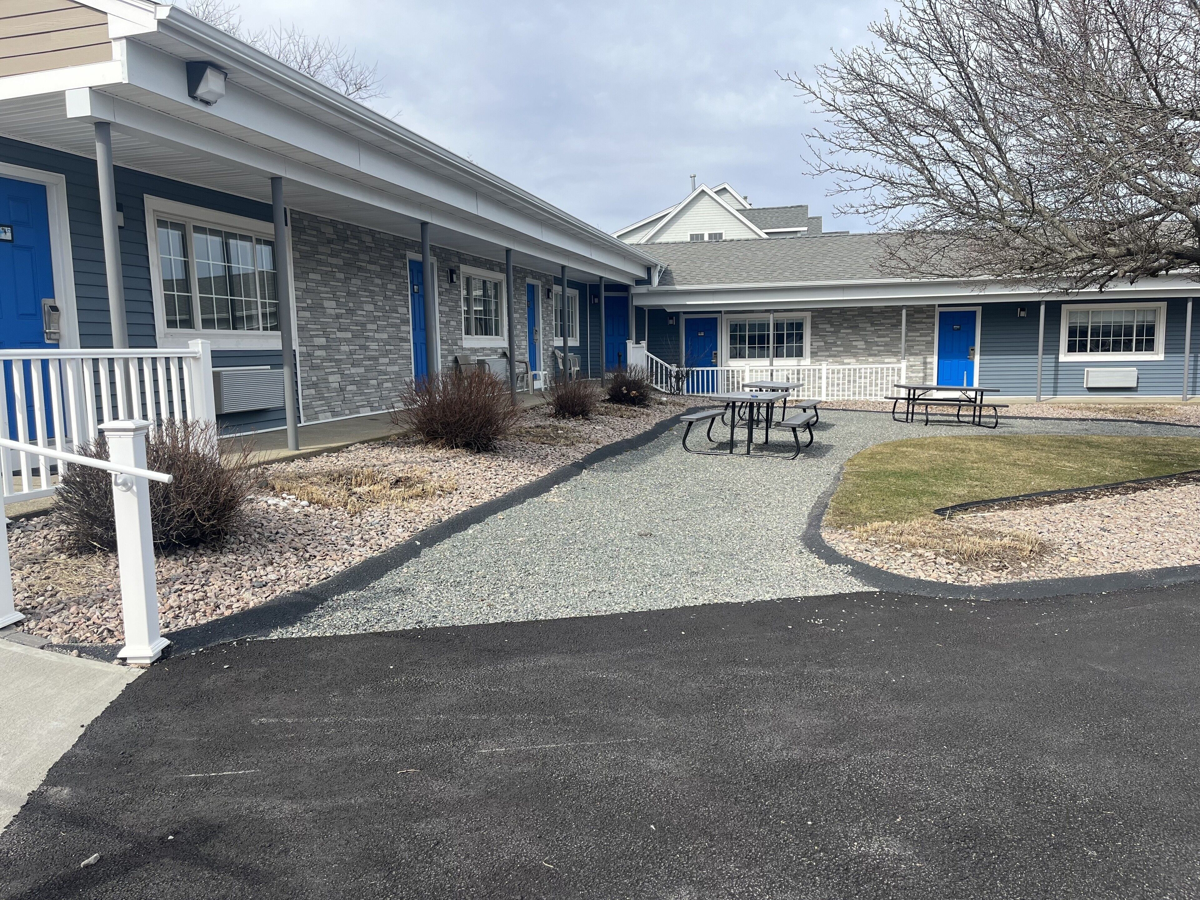 A motel with two-story buildings, outdoor seating, and a gravel pathway.