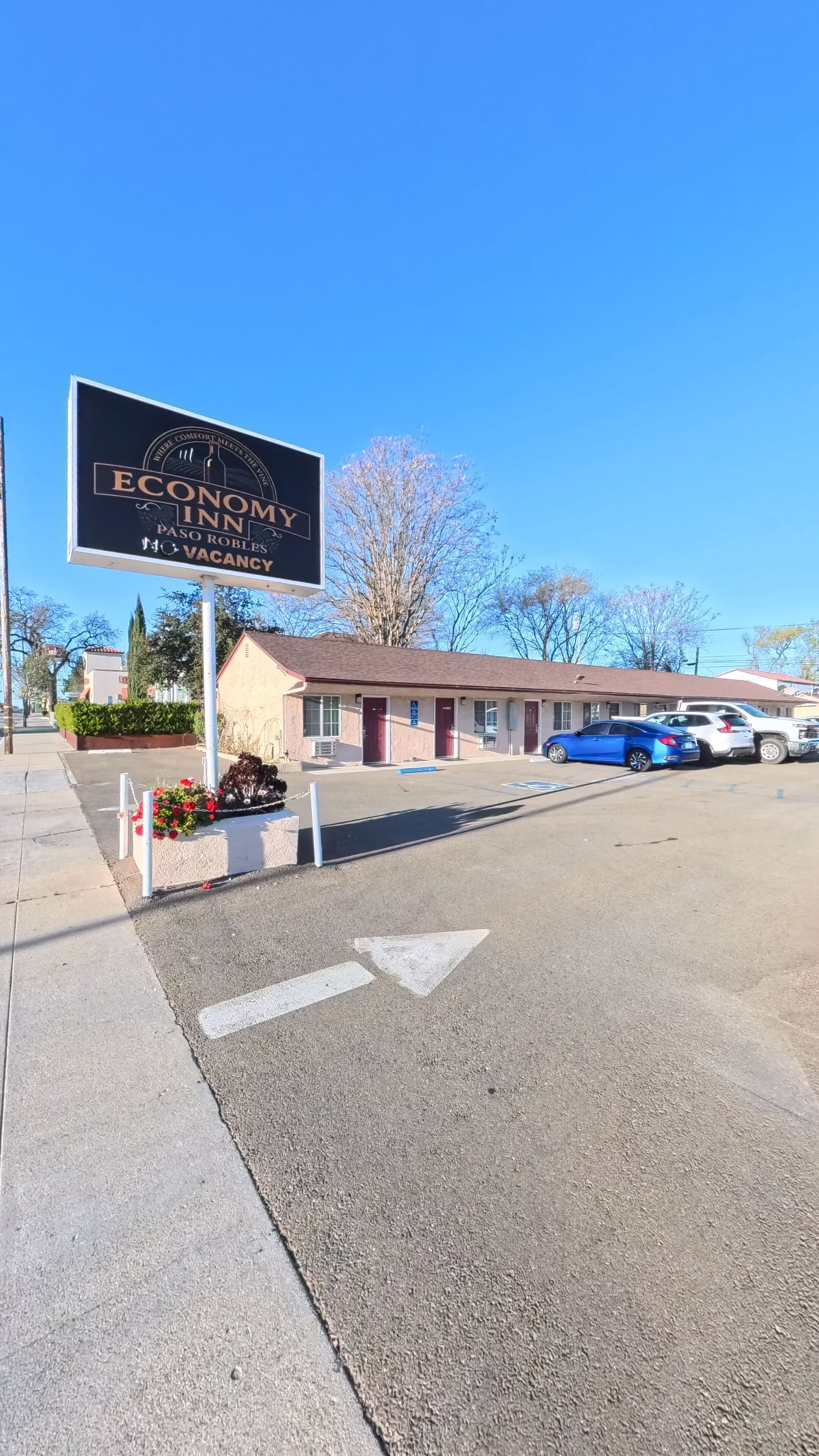 A motel with a signboard, a parking lot, and a building with a red door.
