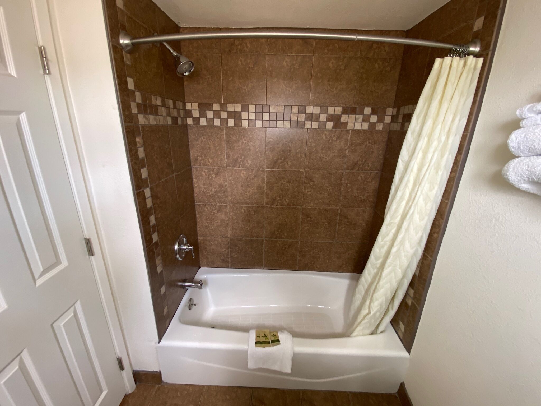 A bathroom with a bathtub, shower, and tiled walls.