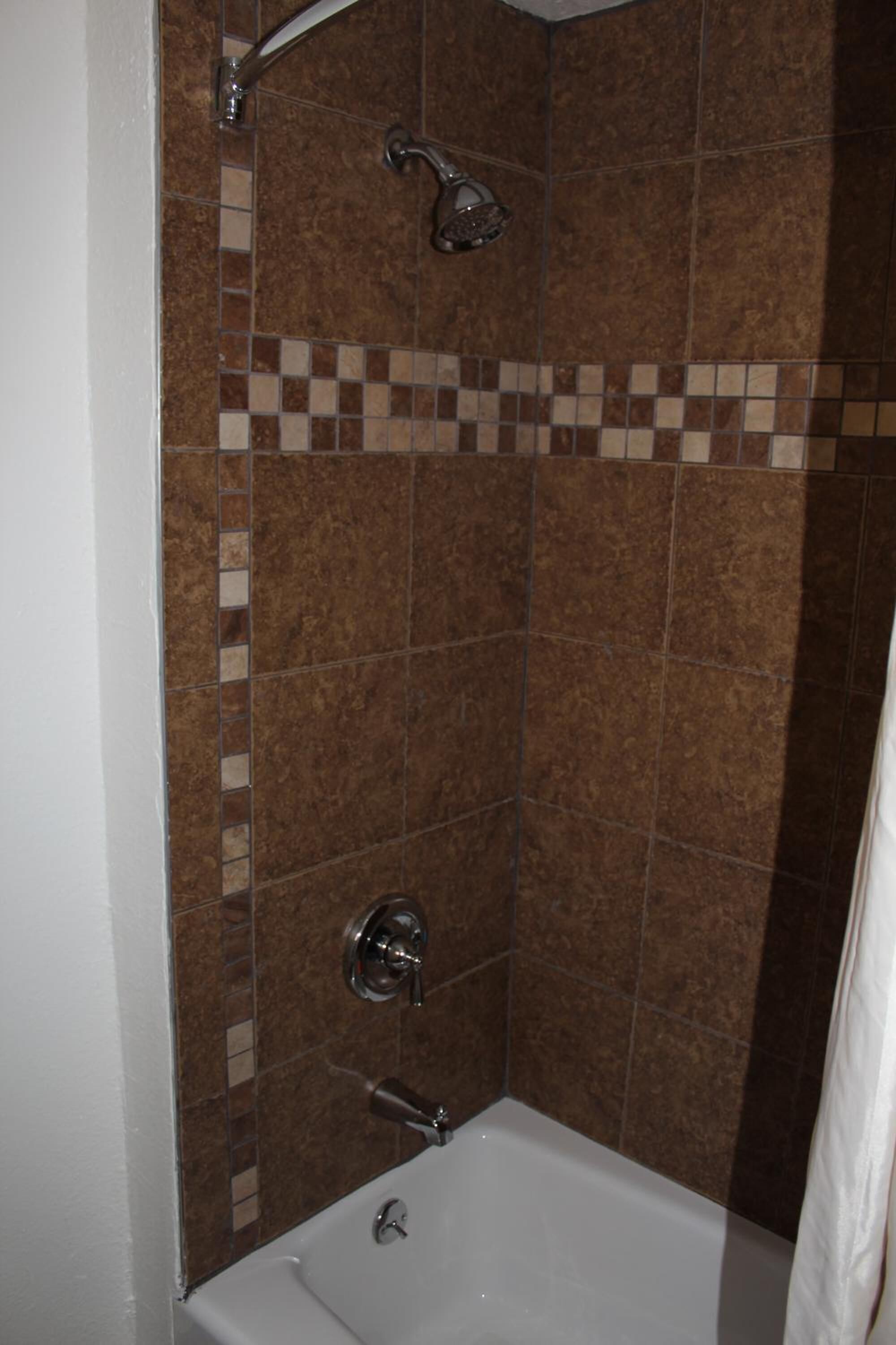 A bathroom with a shower, a bathtub, and tiled walls.