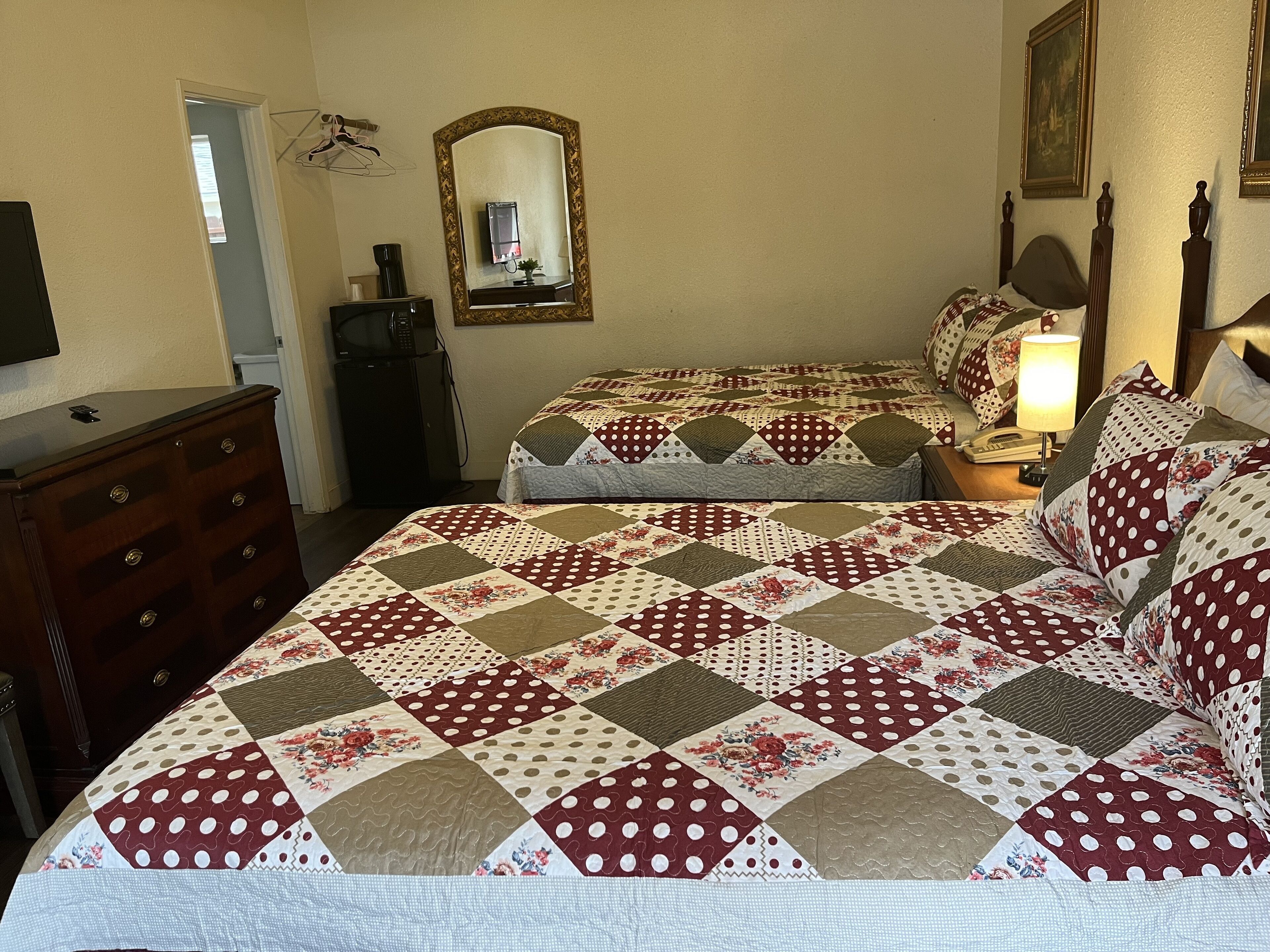 Un dormitorio con dos camas, un aparador, un espejo y una lámpara.