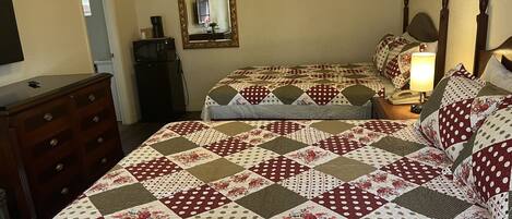 Un dormitorio con dos camas, un aparador, un espejo y una lámpara.